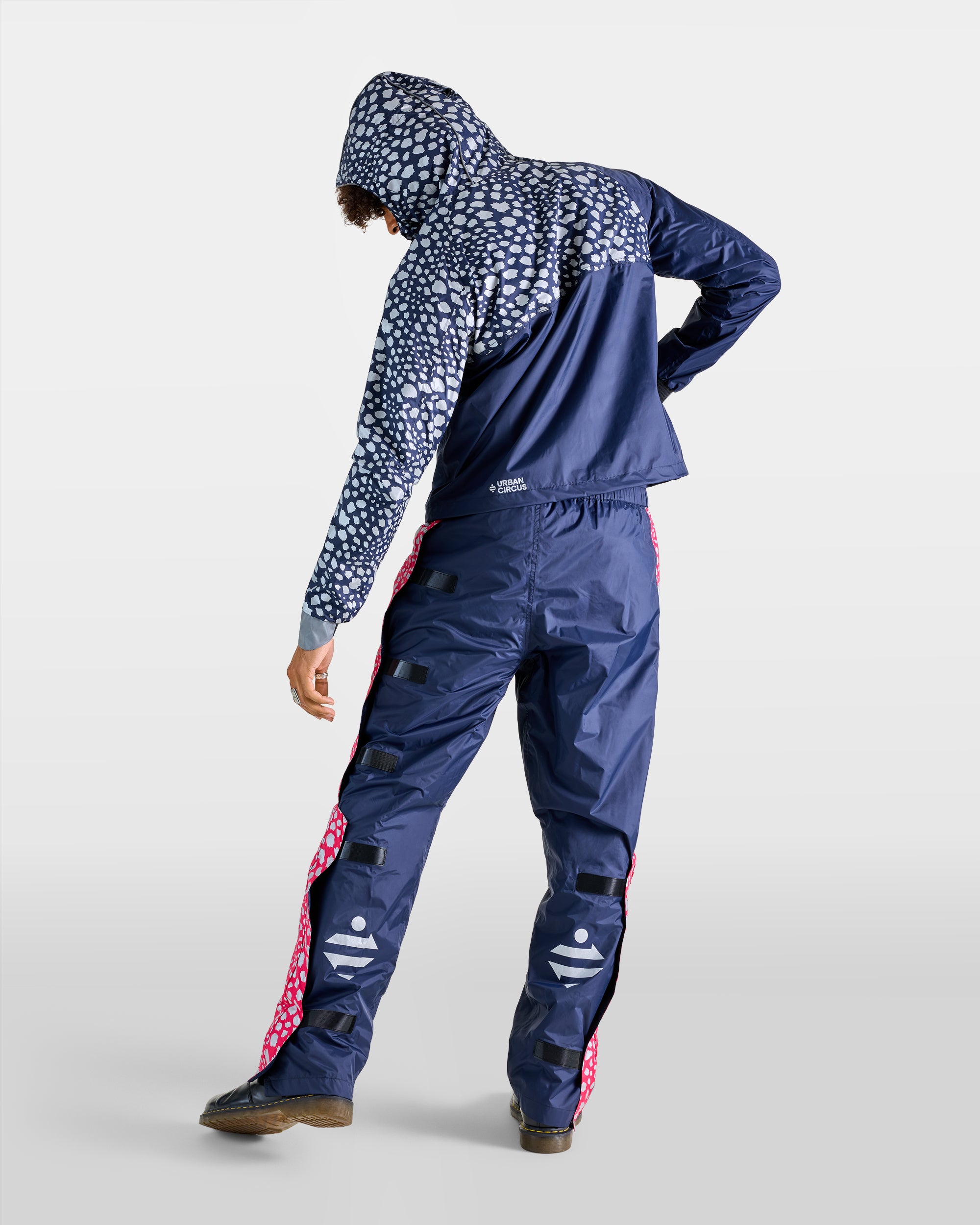 Navy blue waterproof anorak and rain overtrousers set with cheetah patterns, back view of a man
