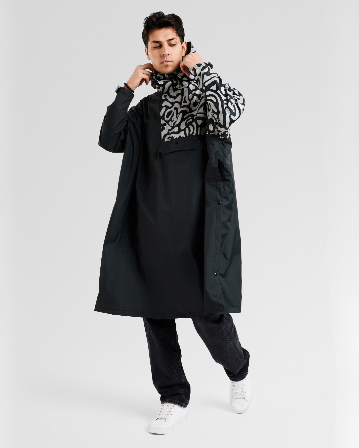 Poncho de pluie noir avec détails réfléchissants, coupe ample pour cyclistes urbains.