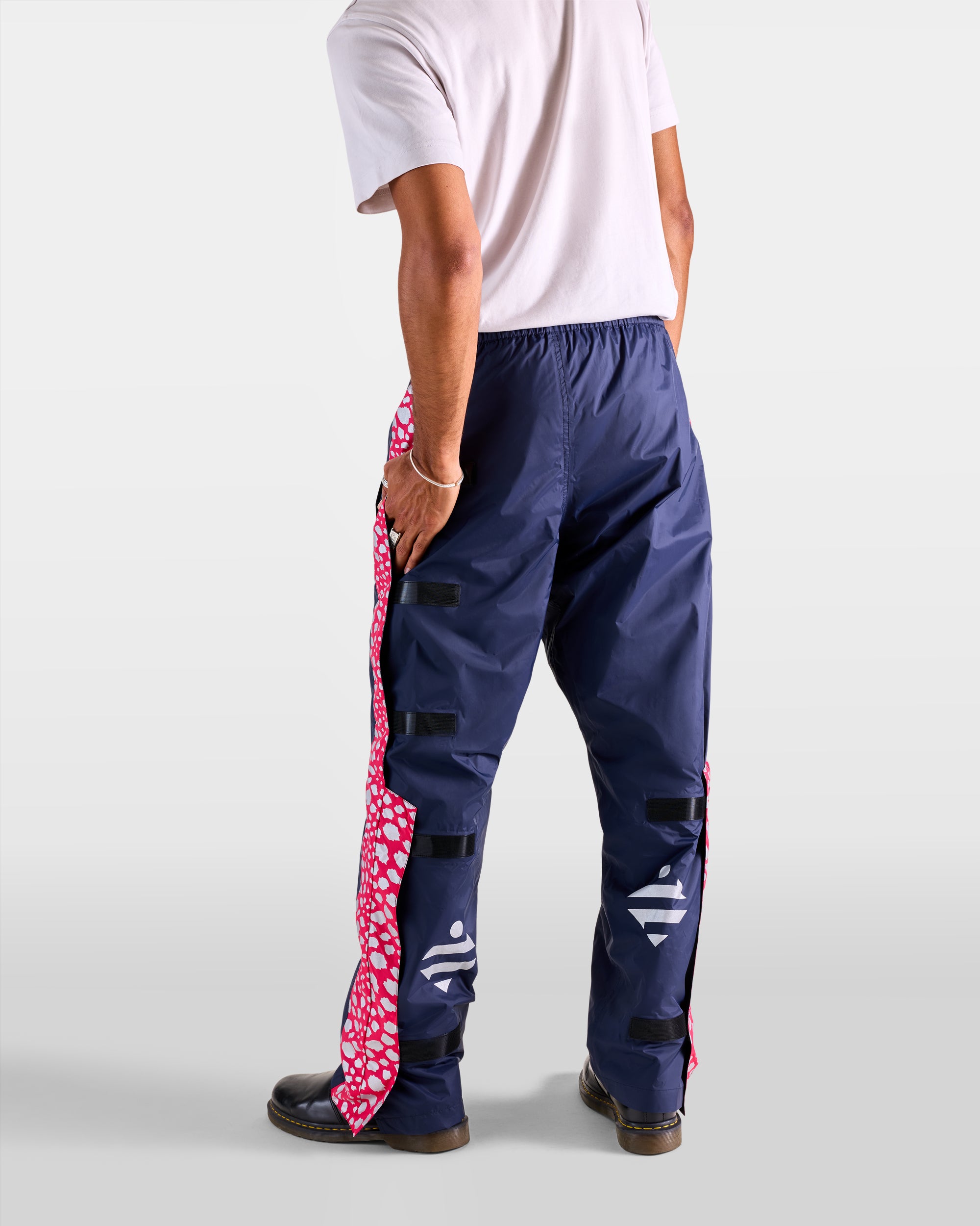 Back view of a man wearing navy blue and pink waterproof cycling rain overtrousers with a pattern