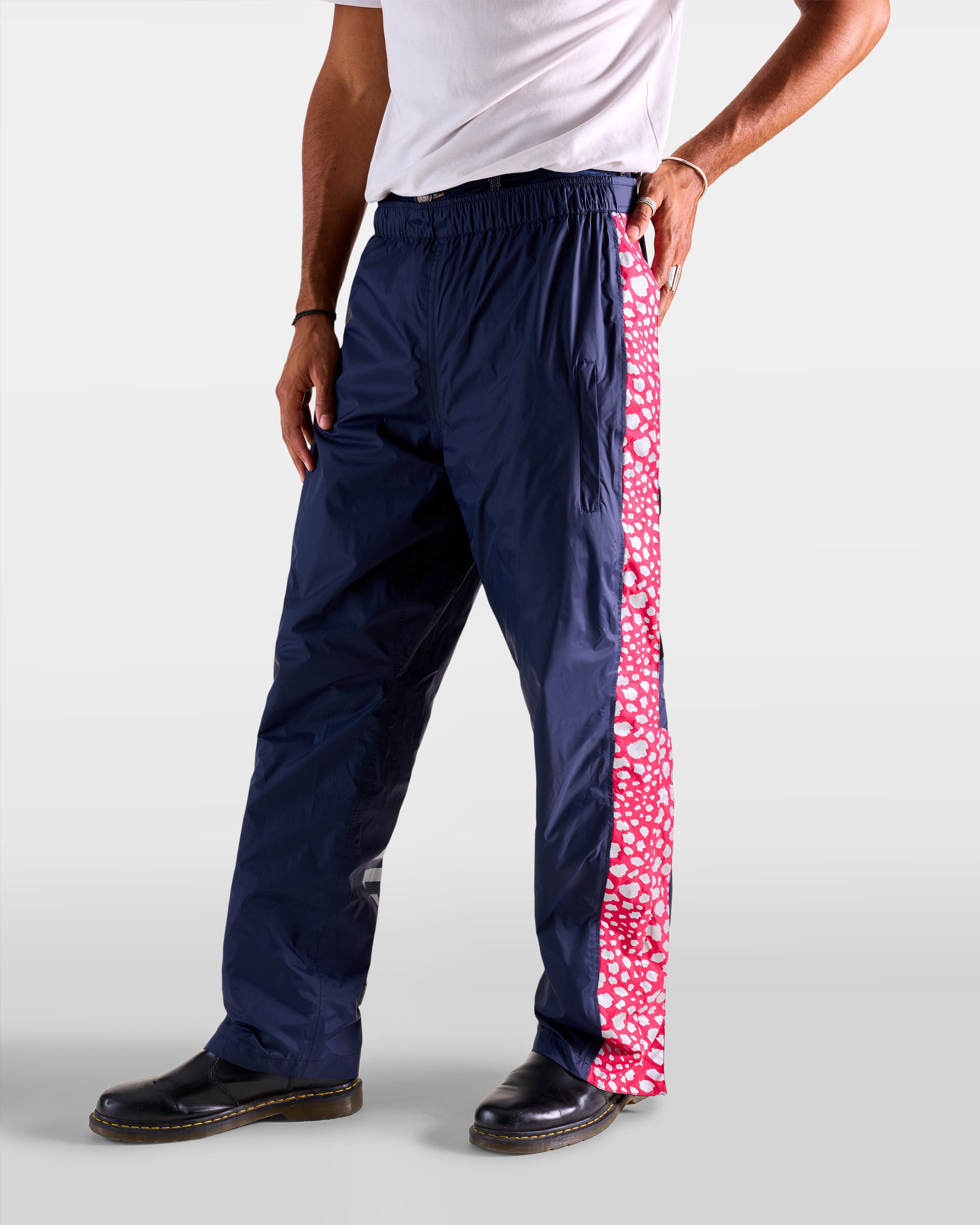 Navy blue and pink waterproof rain overtrousers with cheetah patterns on a man