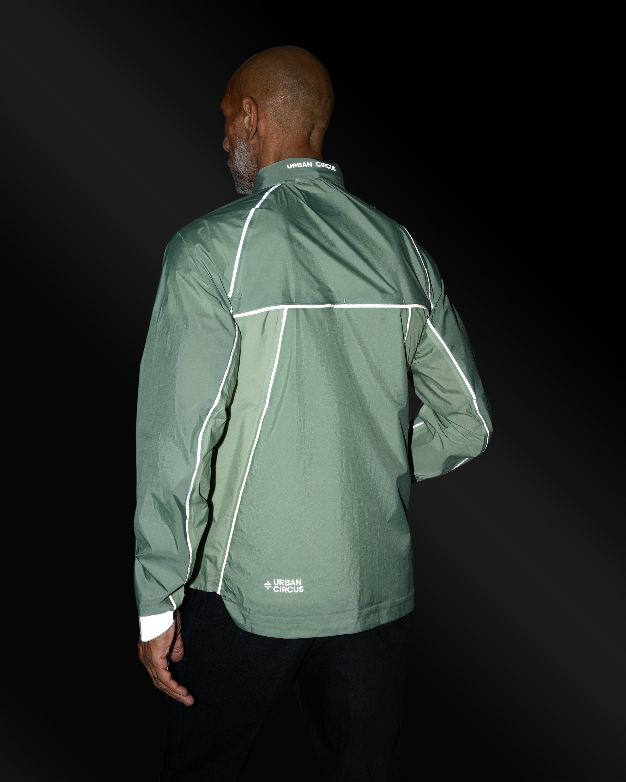 Ultraleichte, atmungsaktive Jacke in Salbeigrün mit reflektierenden Details an einem Mann von hinten